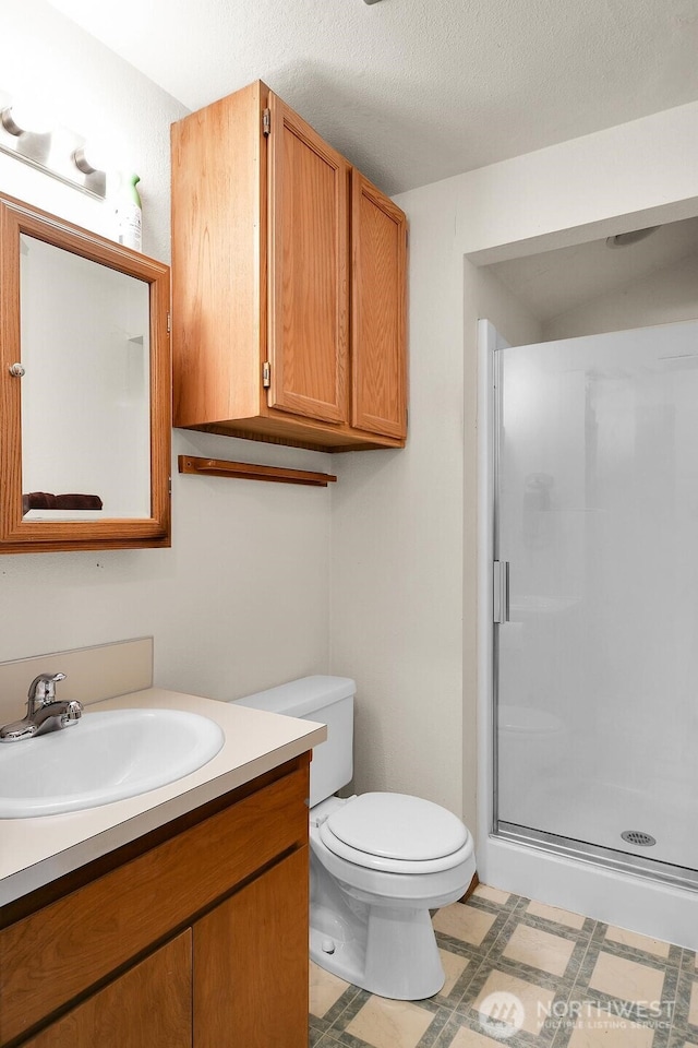 bathroom featuring tile patterned floors, toilet, a textured ceiling, a shower stall, and vanity