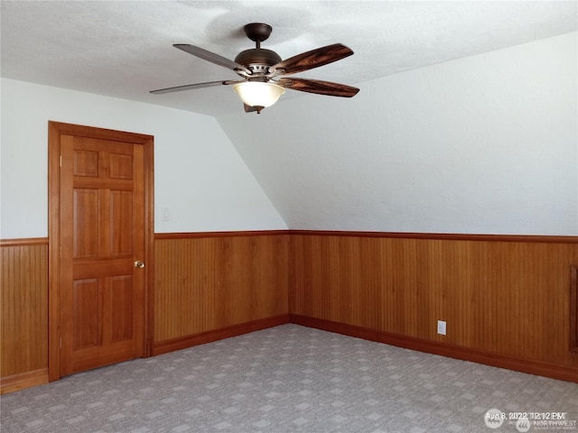 additional living space featuring ceiling fan, wooden walls, carpet flooring, and wainscoting