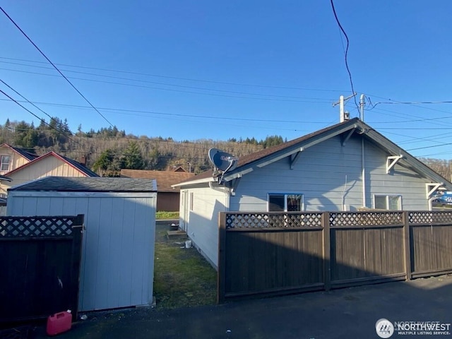 view of side of property featuring an outbuilding, a storage unit, and fence