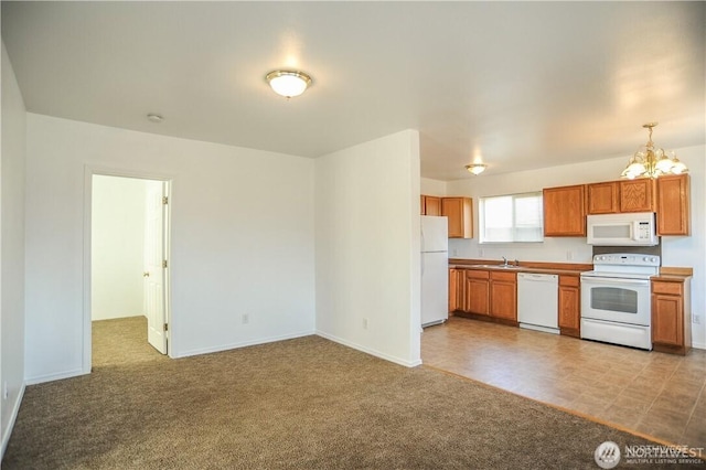 kitchen with white appliances, pendant lighting, light colored carpet, and a chandelier