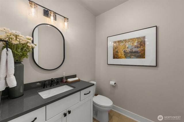 bathroom with vanity, toilet, wood finished floors, and baseboards