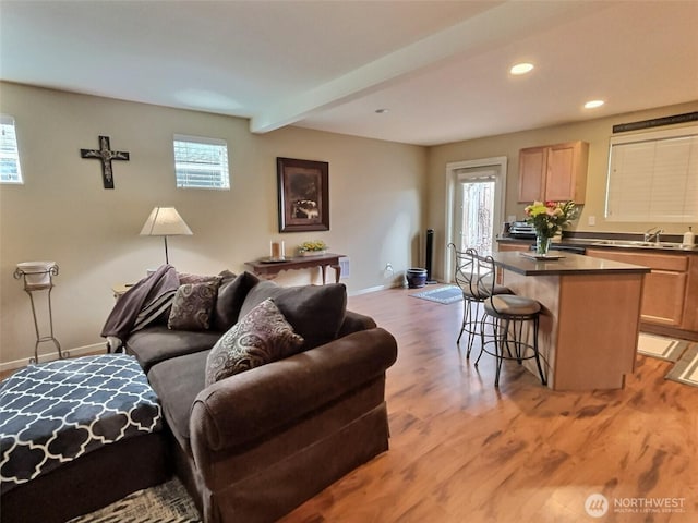 living room with beam ceiling, recessed lighting, baseboards, and light wood finished floors