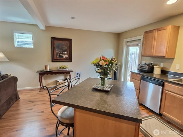 kitchen featuring a kitchen bar, a kitchen island, dark countertops, light wood-style floors, and dishwasher