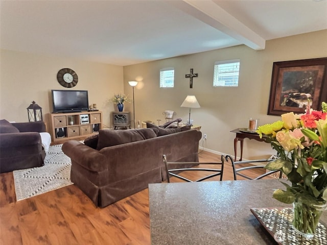 living area with baseboards, beam ceiling, and wood finished floors