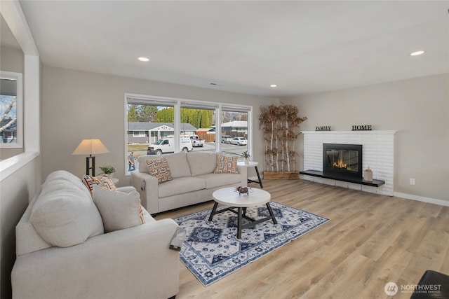 living room featuring recessed lighting, baseboards, wood finished floors, and a fireplace