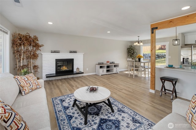 living room with recessed lighting, a notable chandelier, wood finished floors, and a fireplace