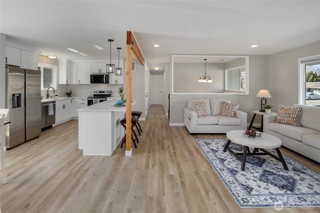 living area with recessed lighting, baseboards, a notable chandelier, and light wood finished floors