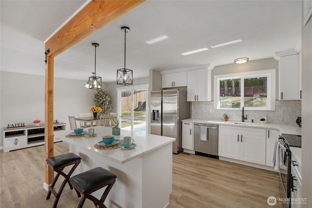 kitchen with backsplash, a breakfast bar, light wood-style floors, stainless steel appliances, and a sink