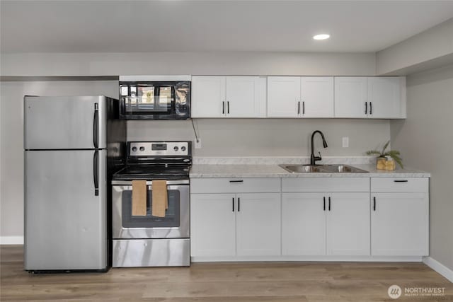 kitchen featuring appliances with stainless steel finishes, white cabinetry, light countertops, and a sink