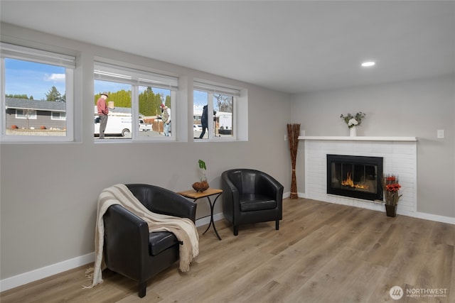 sitting room featuring baseboards, a healthy amount of sunlight, and wood finished floors