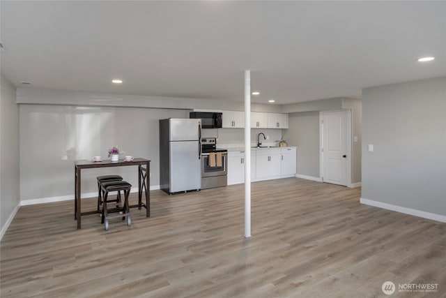 interior space with light wood-style flooring, recessed lighting, and baseboards