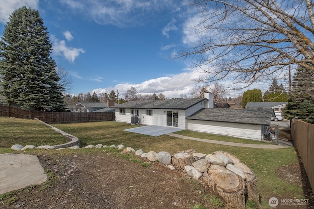 back of property with a lawn, a fenced backyard, a chimney, and a patio area