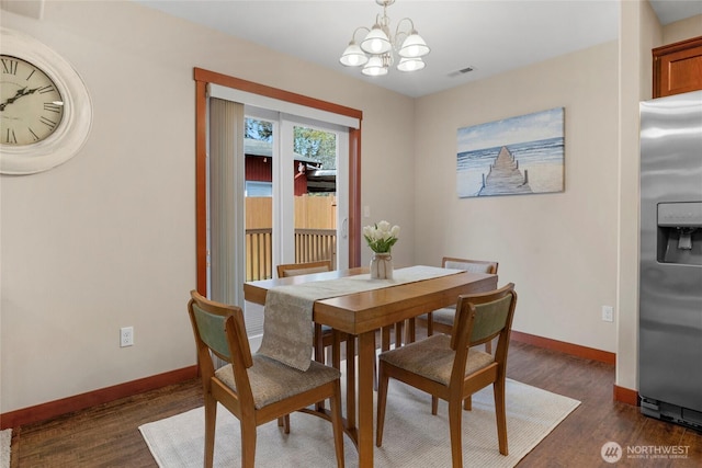 dining area with visible vents, baseboards, dark wood-type flooring, and an inviting chandelier