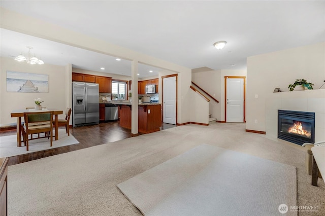 carpeted living area featuring baseboards, a chandelier, stairway, recessed lighting, and a tile fireplace