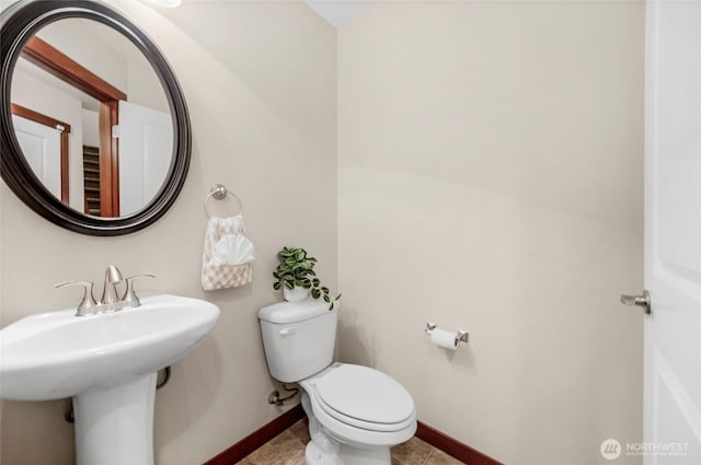 bathroom with baseboards, toilet, and tile patterned flooring