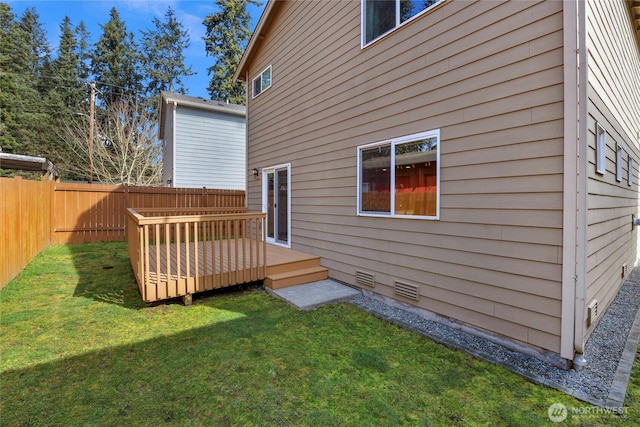 rear view of property featuring a deck, a lawn, and a fenced backyard