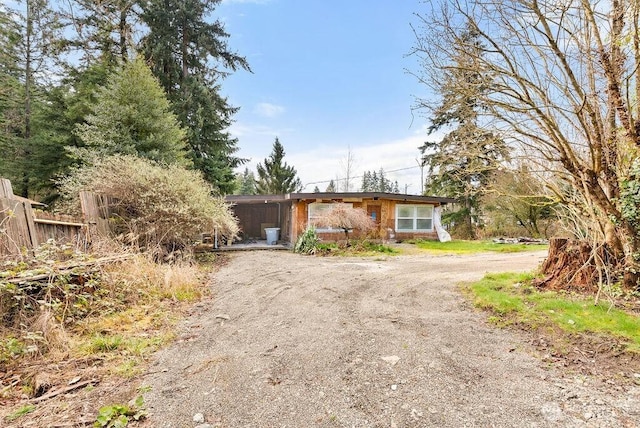 view of front of home with fence and dirt driveway