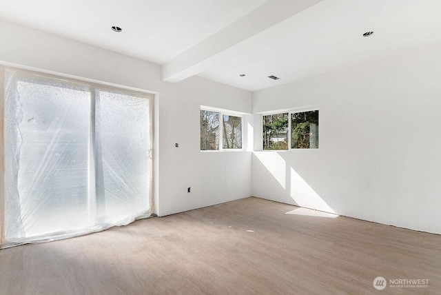 unfurnished room featuring beam ceiling and wood finished floors