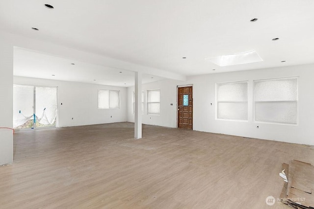 unfurnished living room with light wood-style flooring and a skylight