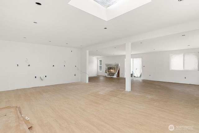 spare room featuring light wood-style flooring and a skylight