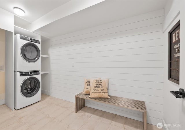 laundry room featuring stacked washer / dryer, laundry area, and wooden walls