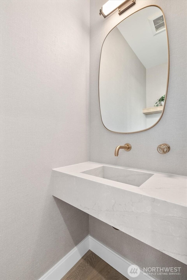 bathroom featuring visible vents, wood finished floors, baseboards, and a sink