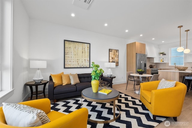 living room with light wood finished floors, visible vents, recessed lighting, and baseboards