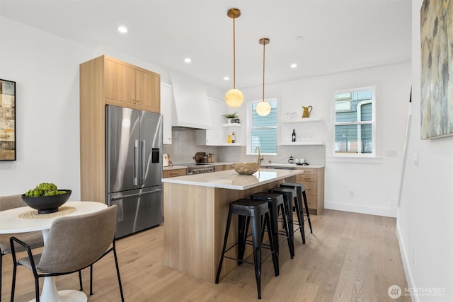 kitchen with a center island, a kitchen bar, high quality fridge, custom exhaust hood, and open shelves