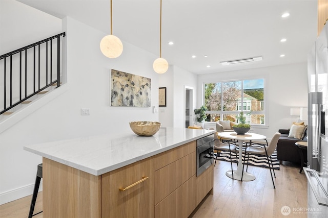 kitchen with modern cabinets, open floor plan, light brown cabinets, and light wood finished floors