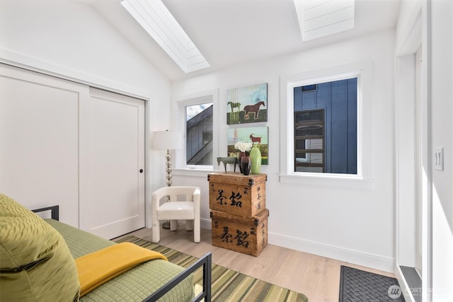 sitting room with lofted ceiling with skylight, baseboards, and wood finished floors