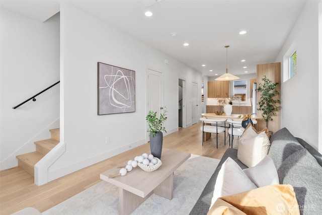 living area with recessed lighting, baseboards, stairs, and light wood-style floors