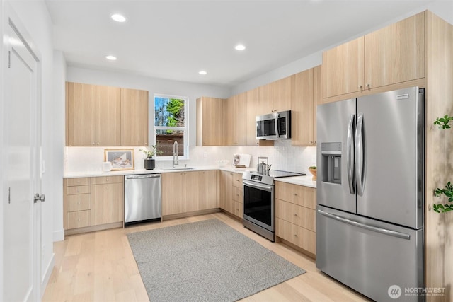 kitchen with tasteful backsplash, light brown cabinets, light countertops, appliances with stainless steel finishes, and a sink