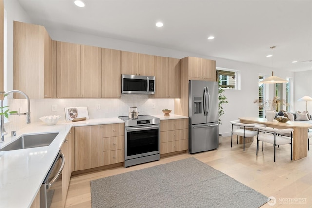 kitchen with modern cabinets, light brown cabinetry, a sink, stainless steel appliances, and light countertops