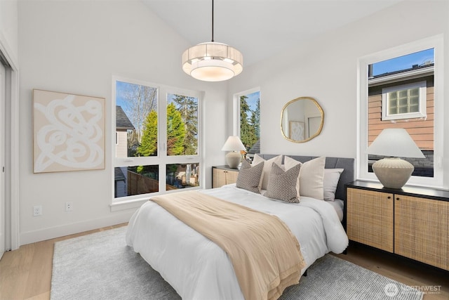 bedroom featuring baseboards, lofted ceiling, and wood finished floors