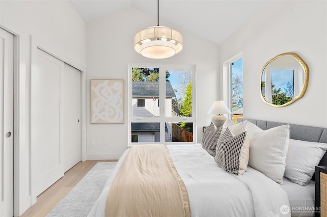 bedroom with baseboards, lofted ceiling, and light wood finished floors