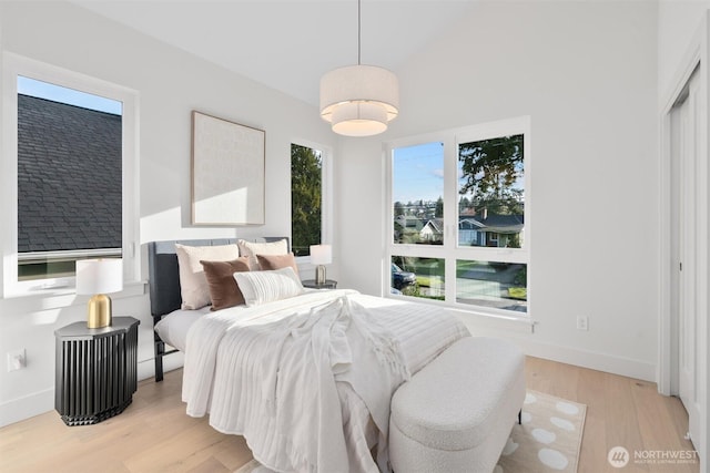 bedroom featuring lofted ceiling, light wood-type flooring, and baseboards