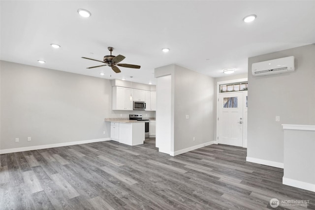 unfurnished living room with recessed lighting, baseboards, wood finished floors, and a wall mounted AC