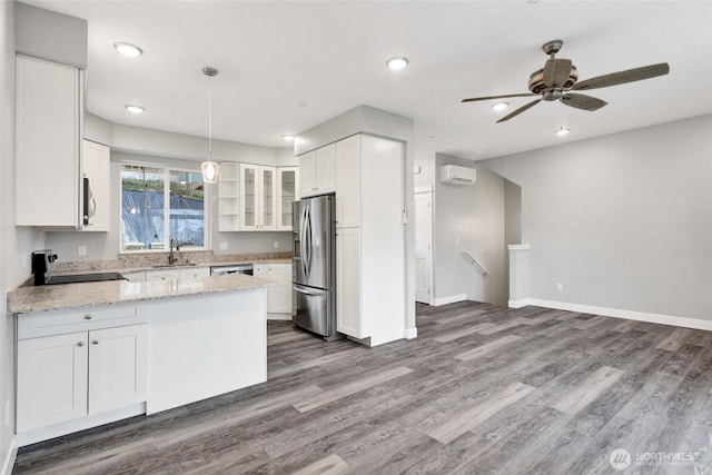 kitchen with glass insert cabinets, appliances with stainless steel finishes, a peninsula, white cabinetry, and a sink