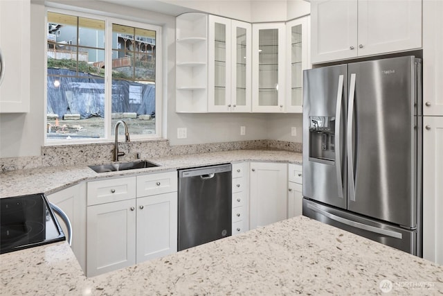 kitchen featuring a wealth of natural light, glass insert cabinets, appliances with stainless steel finishes, and a sink