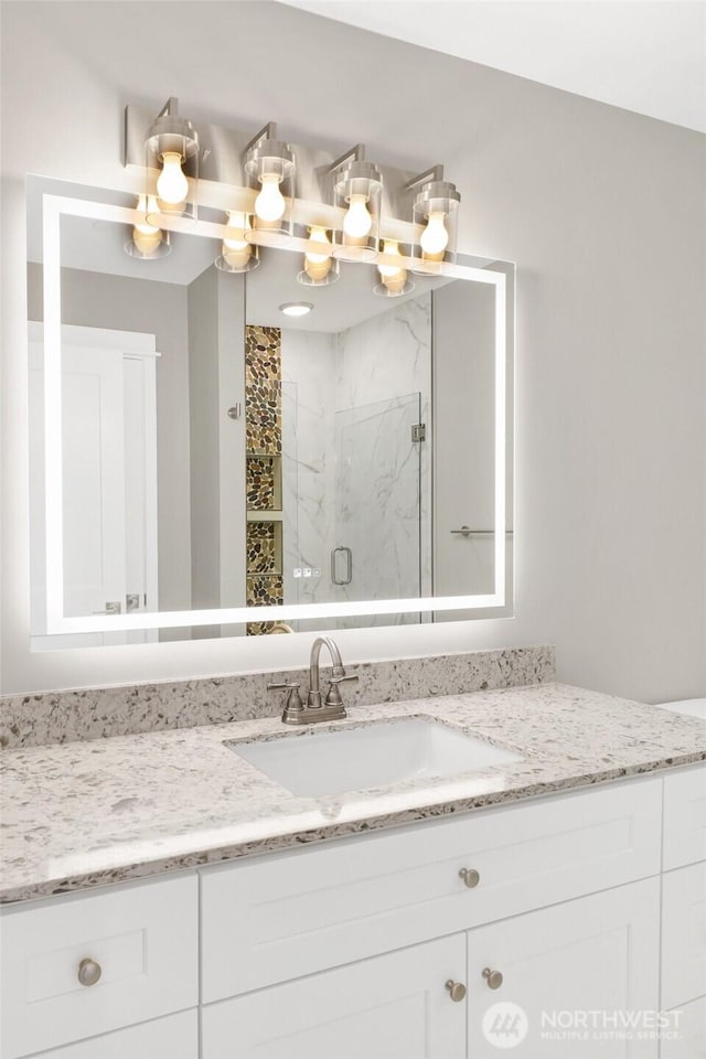 full bath with a marble finish shower and vanity