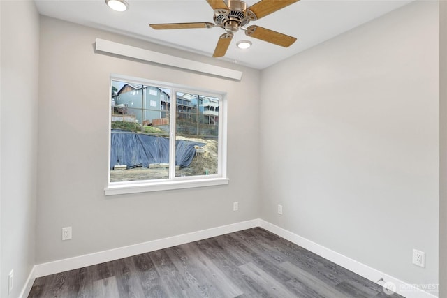 spare room featuring ceiling fan, baseboards, and dark wood-style floors