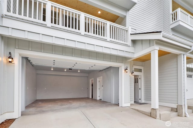 exterior space with concrete driveway, a balcony, and an attached garage