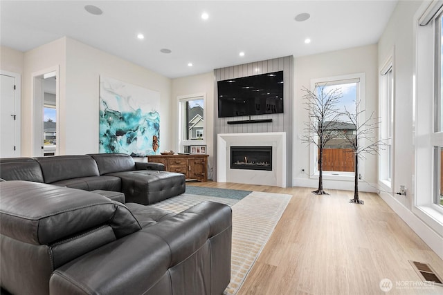 living room with visible vents, baseboards, recessed lighting, light wood-style flooring, and a fireplace