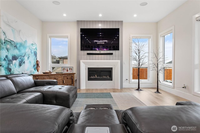 living room featuring a glass covered fireplace, recessed lighting, and wood finished floors