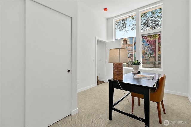 dining space featuring baseboards and light carpet