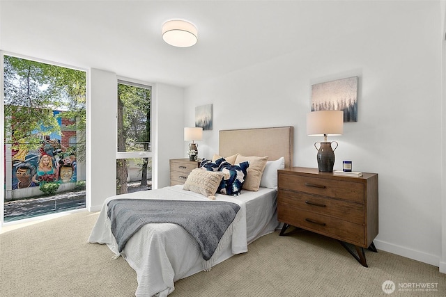 bedroom featuring access to exterior, floor to ceiling windows, light colored carpet, and baseboards