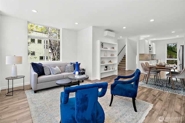 living room with stairway, light wood-style flooring, recessed lighting, and a wall mounted AC