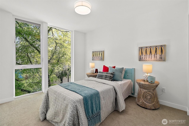 carpeted bedroom featuring a wall of windows and baseboards