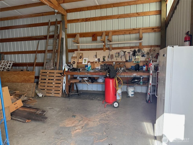 garage with metal wall, a workshop area, and freestanding refrigerator