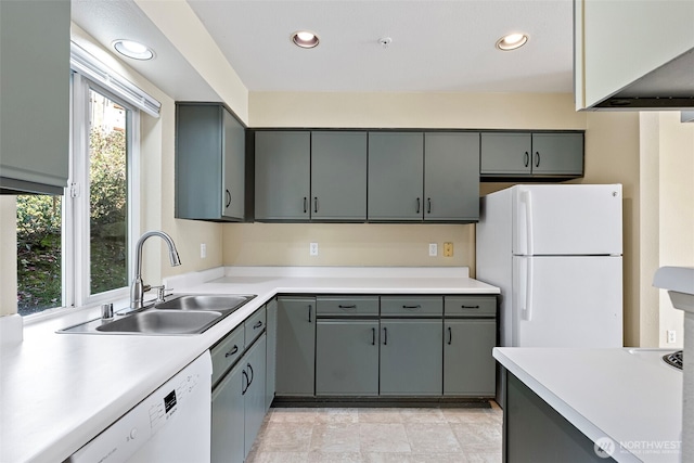 kitchen featuring a sink, white appliances, gray cabinetry, and light countertops